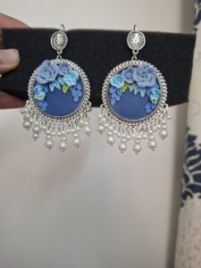 "Handcrafted blue circular jhumkas with 3D floral rose design, silver border, and hanging pearl drops." 